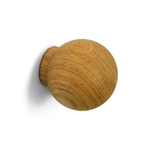 Könnte beinhalten: Ein runder Holz-Knopf mit einer natürlichen Holz-Oberfläche. Der Knopf ist an einer Wand befestigt.