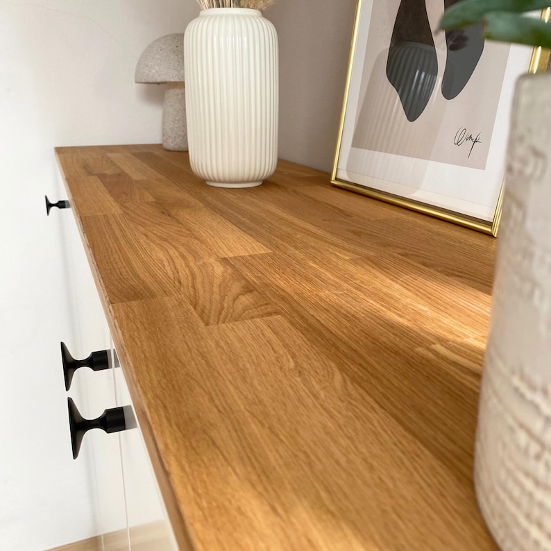 Detailbild von einem Beispiel für ein Projekt mit einer Massivholzdeckplatte nach Maß aus Eiche von Omformo. Hier als DIY Sideboard mit IKEA Metod Elementen und Möbelknöpfe Platta in Schwarz von Omformo. Dekoriert mit Pflanzen, einer weißen Vase und einer beigen Pilzlampe um ein Wohnbeispiel für einen modernes Sideboard darzustellen.