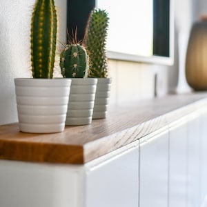 Beispiel für ein Projekt mit einer Deckplatte nach Maß von Omformo. Hier als Badablage für einen Vorsprung in der Wand. Dekoriert mit Pflanzen und einer Lampe um ein Wohnbeispiel für ein schlichtes Bad darzustellen.