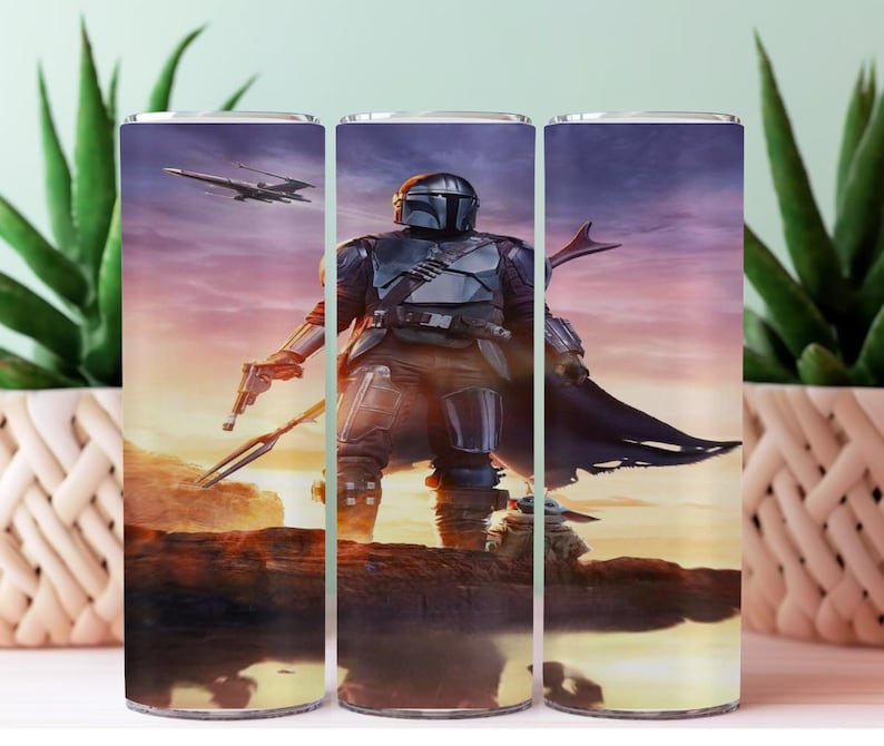 May include: A stainless steel tumbler featuring a detailed image of The Mandalorian from the Star Wars series. The design includes the character in armor, a blaster, and a spaceship against a sunset backdrop. The tumbler is cylindrical and likely holds approximately 20 ounces.