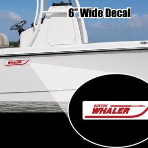 May include: A white boat with a red and white "Boston Whaler" decal. The decal is 6 inches wide and features the brand name and a stylized arrow. The boat is on the water under a blue sky.