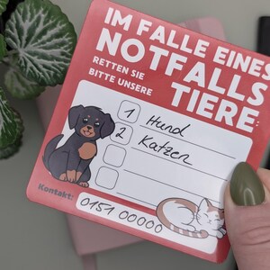 May include: A red card with the text "IM FALLE EINES NOTFALLS TIERE" and "RETTEN SIE BITTE UNSERE". It features illustrations of a dog and a cat, with space to write contact information and pet details.