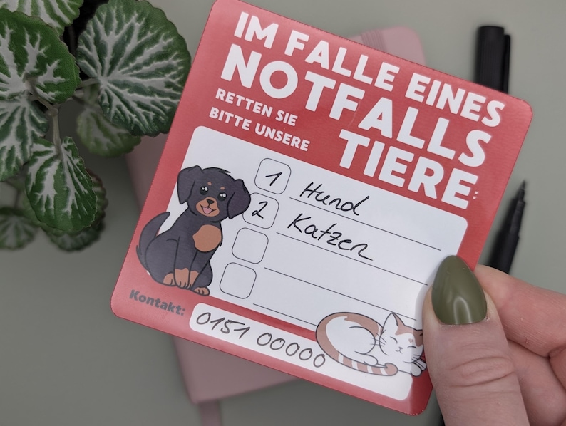 May include: A red card with the text "IM FALLE EINES NOTFALLS TIERE" and "RETTEN SIE BITTE UNSERE". It features illustrations of a dog and a cat, with space to write contact information and pet details.
