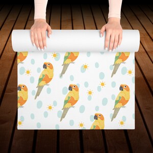 May include: White yoga mat with a repeating pattern of yellow and orange parrots on a white background with blue and yellow accents.
