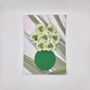 Peut inclure: Un vase vert avec un bouquet de fleurs en papier vert clair. Le vase et les fleurs sont sur un fond blanc avec un motif rayé vert et blanc.