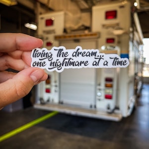 May include: A white sticker with black text that reads "living the dream... one nightmare at a time".