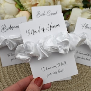 May include: White satin scrunchie with a card that says "Maid of Honour" and "To have and to hold your hair back".