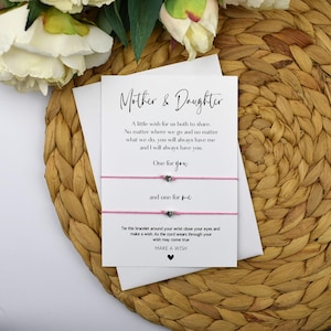 May include: A card with the text "Mother & Daughter" and a message about a wish for both to share. Two pink friendship bracelets with silver heart charms are attached to the card. The card also says "Make a Wish".