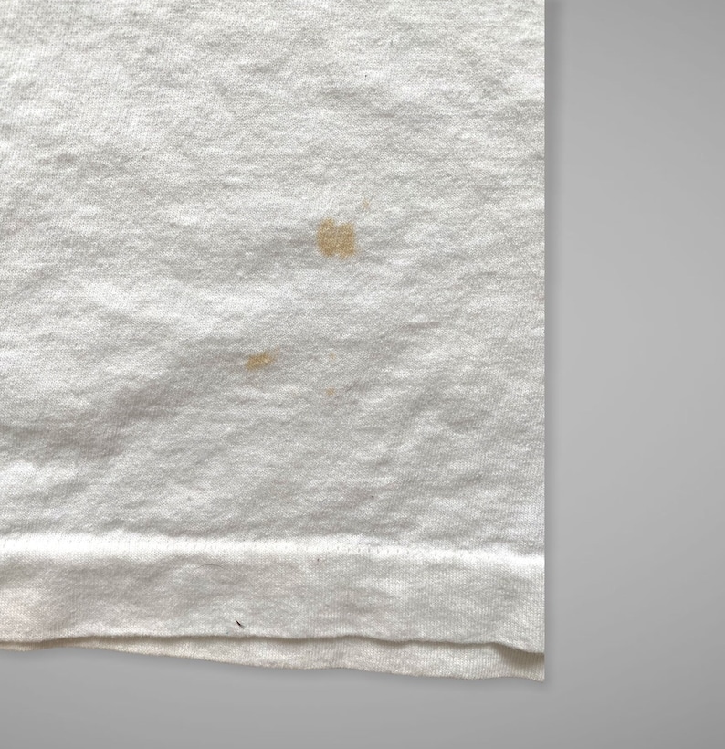 May include: White t-shirt with two small brown stains.