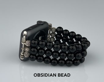 Puede incluir: Pulsera de reloj de cuentas de obsidiana negra con detalles plateados. La pulsera está hecha de múltiples hileras de cuentas y está diseñada para adaptarse a un reloj inteligente.