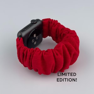Könnte beinhalten: Ein rotes Stoffarmband mit einer schwarzen Apple Watch. Das Armband besteht aus einem weichen, dehnbaren Material und hat einen gerafften Look. Der Text "LIMITIERT EDITION!" ist unter der Uhr gedruckt.
