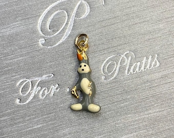 May include: A gold-toned bunny charm with gray and cream enamel details. The bunny has a gold-colored loop for attaching to a bracelet or necklace. The background is a gray fabric with the words "For Platts" and a stylized "P" embroidered in white.