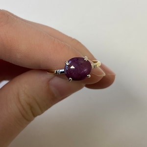 Può includere: Un anello d'oro con una grande pietra preziosa rotonda di colore viola scuro incastonata in una montatura a griffe d'argento.