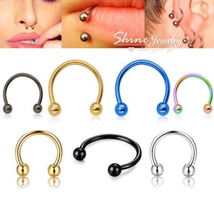 May include: A selection of horseshoe-shaped body jewellery in gold, black, blue, and iridescent colours. Each piece has a curved bar with a ball at each end. The image also shows examples of the jewellery being worn.