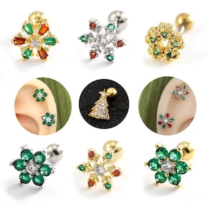 May include: A selection of Christmas-themed stud earrings. Designs include a snowflake, a Christmas tree, and floral shapes, all adorned with colourful gemstones in gold and silver settings. The earrings are shown individually and in pairs.
