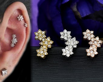 May include: Three different colored ear cartilage earrings with a flower design. Each earring has three flowers with clear rhinestones.