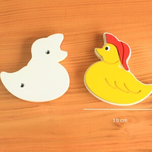 May include: Two wooden duck toys, one white and one yellow with a red hat. Both ducks are 10 cm wide.