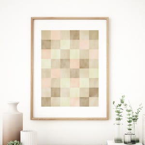 以下が含まれることがあります： 茶色、ベージュ、ピンクの正方形で構成された幾何学模様の額装されたプリント