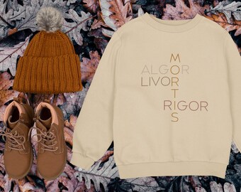 May include: A fall-themed image featuring a tan sweatshirt with the text "ALGOR LIVOR MORTIS RIGOR S", a brown knit beanie with a pom-pom, and brown boots. The items are arranged on a background of autumn leaves.