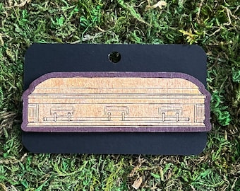 May include: A wooden coffin cutout with a brown stain and a burgundy border. The coffin has a simple design with a raised lid and decorative details.
