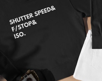 May include: Black sweatshirt with white text that reads "SHUTTER SPEED & F/STOP & ISO."