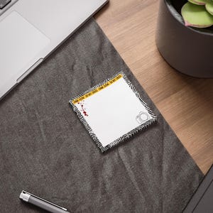 May include: A white notepad with a black and white zigzag border, a camera icon, and a blood spatter design. The notepad has a yellow crime scene tape design with the text "CRIME SCENE - DO NOT CROSS".