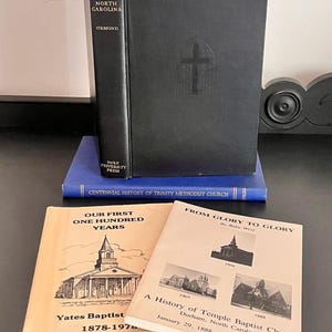 May include: A collection of four books including a black hardcover titled The Country Church in North Carolina, a blue book titled Centennial History of Trinity Methodist Church, and two tan softcover books titled Our First One Hundred Years and From Glory to Glory.