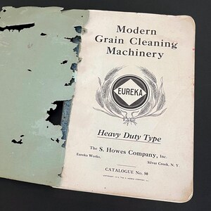 May include: An open vintage catalog titled "Modern Grain Cleaning Machinery." The cover features the word "EUREKA" inside a circle, surrounded by wheat stalks. The catalog is tattered with a light green cover.