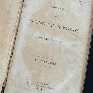 May include: A vintage book titled "Report of the Commissioner of Patents for the Year 1853. Agriculture."  The book is printed in black ink on a cream-colored page. The text is slightly faded.