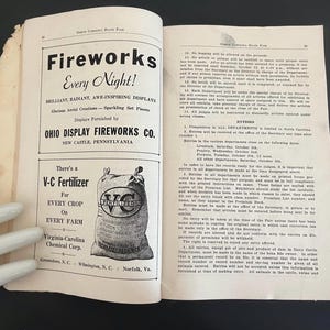May include: Open book with text and illustrations. The left page features a fireworks advertisement with the text "Fireworks Every Night!" and the Ohio Display Fireworks Co. The right page contains text about the North Carolina State Fair.
