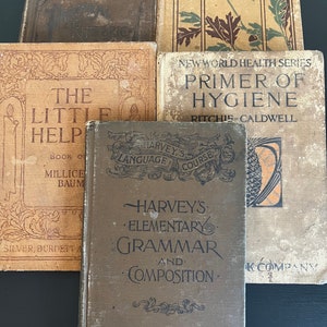 May include: A collection of antique books with aged covers. Titles include "Harvey's Elementary Grammar and Composition," "Primer of Hygiene," and "Heart of Oak Books." The books are in various shades of brown and tan, with decorative text and illustrations.