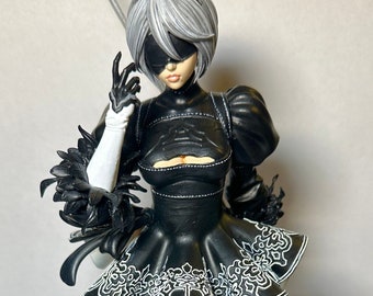 May include: A black and white figurine of a female character wearing a black dress with white trim and a black eye patch. She is holding a sword in her right hand and is standing on a black base.