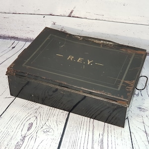 May include: A vintage green metal box with a black handle and the inscription "R.E.Y." on the lid.