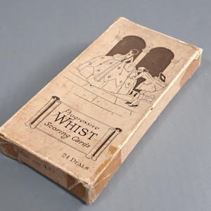Puede incluir: Caja vintage de "Progressive Whist Scoring Cards". La caja rectangular tiene una combinación de colores marrón y beige. La parte delantera presenta una ilustración de dos figuras con ropa de época. El texto en la caja dice "Progressive Whist Scoring Cards" y "24 Deals".