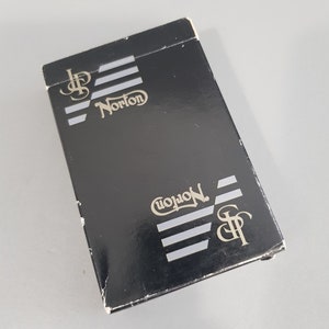 May include: Black playing card deck box with the text "J.P. Norton" in silver lettering on the front and back.