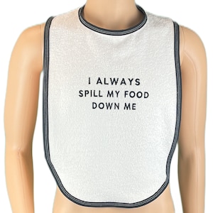 May include: White bib with black trim and the text "I ALWAYS SPILL MY FOOD DOWN ME" embroidered on it.