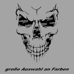 Peut inclure: Un graphisme de crâne noir avec le texte "FREAKY PLOTT" remplissant les orbites et le texte "große Auswahl an Farben" en bas, sur fond gris.