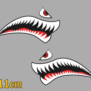 Könnte beinhalten: Zwei weiße und rote Haimaul-Aufkleber mit einem roten Auge. Die Aufkleber sind 11 cm lang.