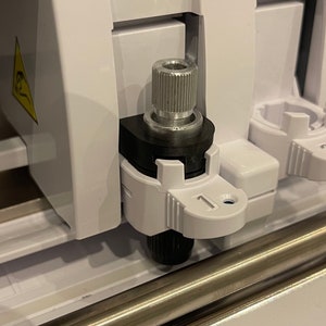 Könnte beinhalten: Nahaufnahme eines weißen und schwarzen Werkzeugs mit einem silbernen Knopf. Das Werkzeug ist mit der Nummer "1" gekennzeichnet.