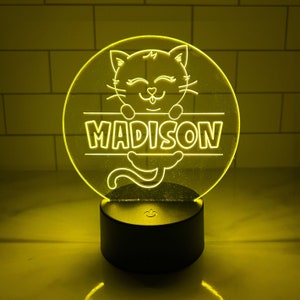 May include: A yellow LED night light with a clear acrylic panel featuring a cartoon cat with the name "MADISON" written below it.