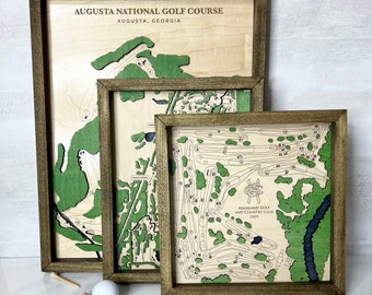 May include: Three wooden framed golf course maps with green and brown details. The largest map is labeled "Augusta National Golf Course, Augusta, Georgia". The smallest map is labeled "Highland Golf and Country Club 1919".