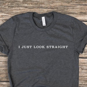 Puede incluir: Camiseta gris oscuro con el texto "I JUST LOOK STRAIGHT" impreso en blanco en la parte delantera.