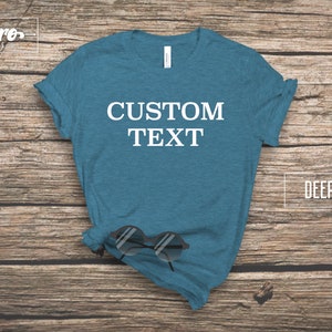 May include: A deep teal t-shirt with the text "CUSTOM TEXT" printed in white on the front.