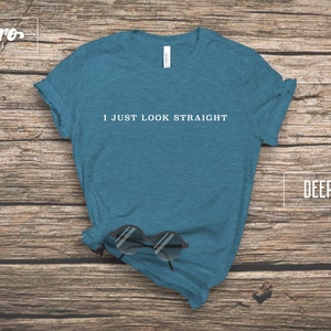 May include: A deep teal t-shirt with the text "I just look straight" printed in white on the front.