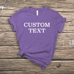 May include: A lilac t-shirt with the text "CUSTOM TEXT" printed in white on the front.