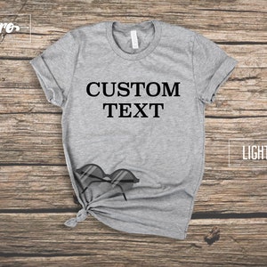 May include: A light grey t-shirt with the text "CUSTOM TEXT" printed in black on the front.
