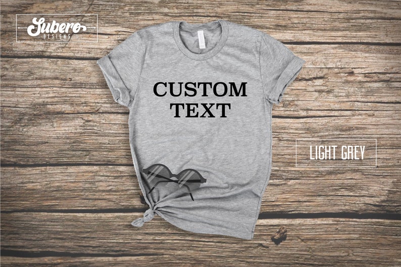 May include: A light grey t-shirt with the text "CUSTOM TEXT" printed in black on the front.