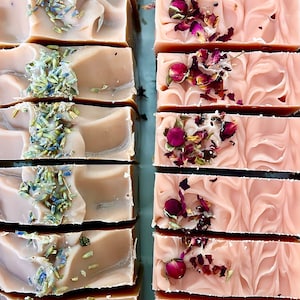 May include: Two rows of handmade soap bars. The top row features lavender-scented soap with dried lavender buds. The bottom row features rose-scented soap with dried rose petals.