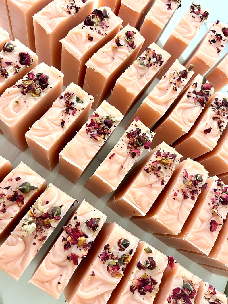 May include: A collection of handmade soap bars with a pink base and dried rose petals embedded in the soap.