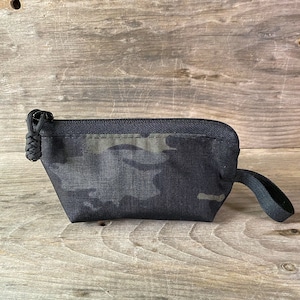 May include: A small black zippered pouch with a camouflage pattern and a black strap.